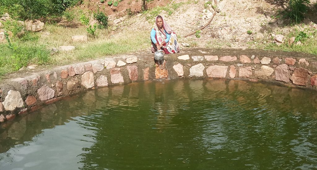 A woman collects water from a well that was recharged due to water harvesting in Lalitpur district of Bundelkhand. 